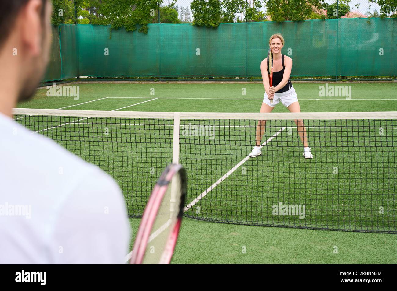 Homme et femme jouant au tennis sur le court de tennis, gens en vêtements de sport Banque D'Images