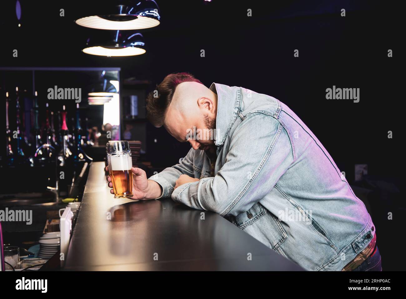 un homme brutal ivre avec un cocktail alcoolisé dans un verre. Le concept des mauvaises habitudes et de la dépendance à l'alcool. Un homme solitaire et triste s'ivre dans un pub irlandais Banque D'Images