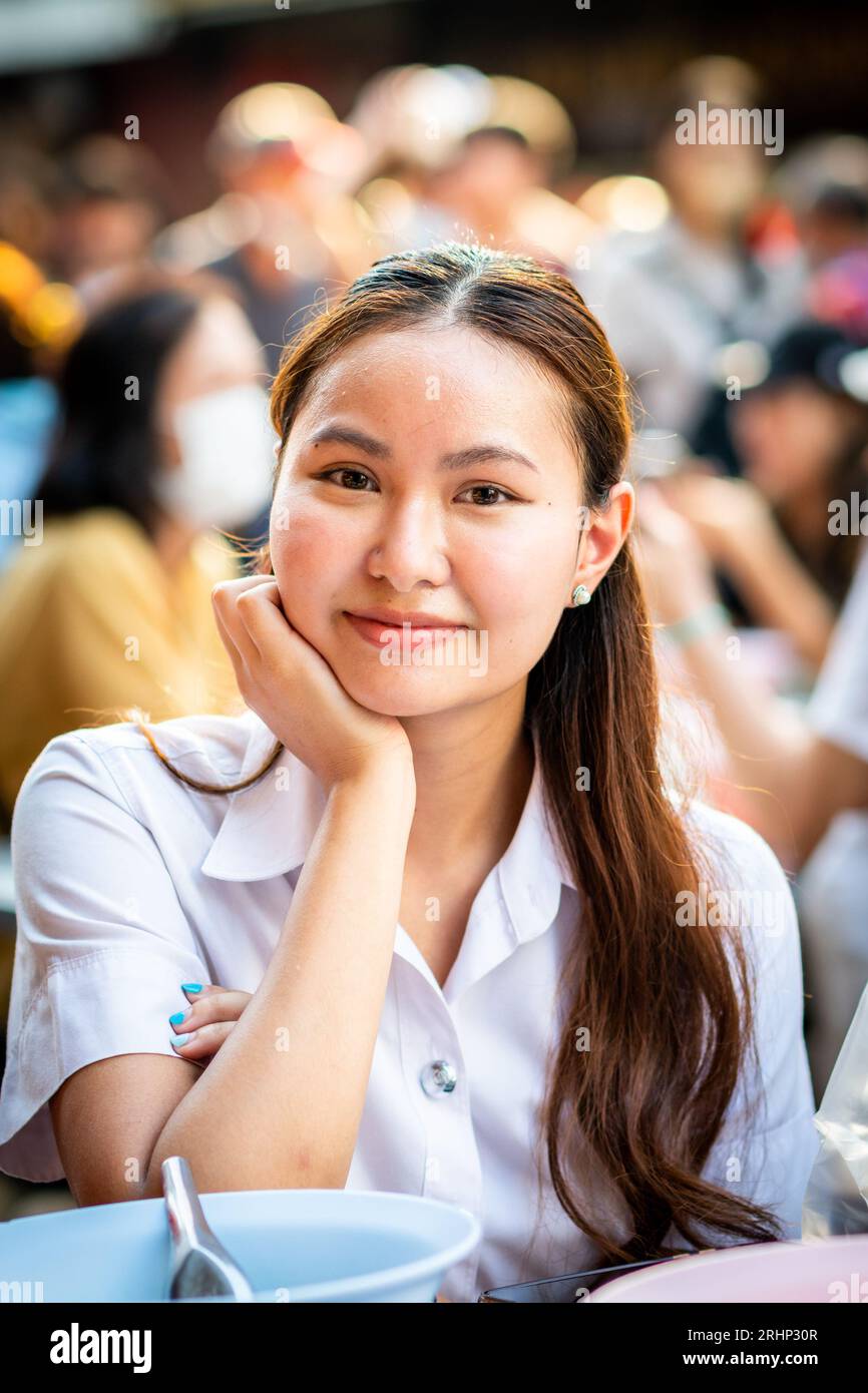Une belle jeune fille thaïlandaise sourit pour mon appareil photo tout en déjeunant sur Yaowarat Rd. China Town, Bangkok, Thaïlande. Banque D'Images
