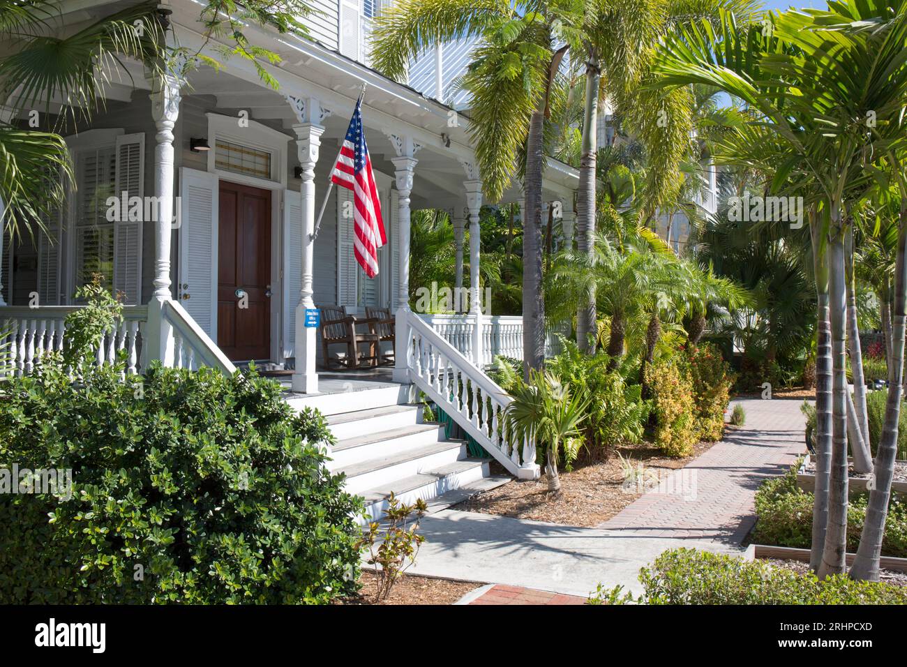 Key West, Floride, États-Unis. Vue à travers les palmiers à la véranda en bois de Chelsea House, une auberge historique sur Truman Avenue, vieille ville. Banque D'Images
