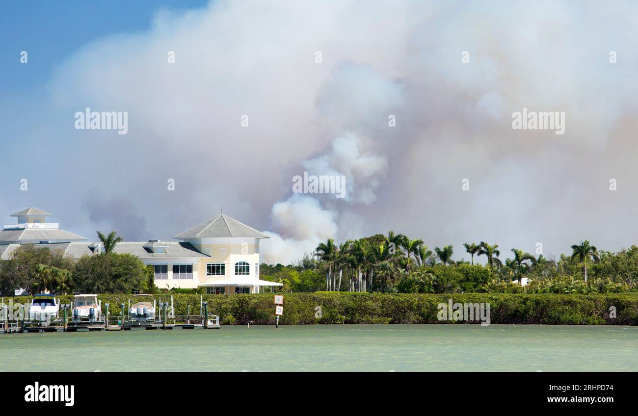 Naples, Floride, États-Unis. Nuages de fumée au-dessus de la baie de Naples s'élevant d'un feu de brousse dans la forêt d'État de Picayune Strand causé par un incendie prescrit échappé. Banque D'Images