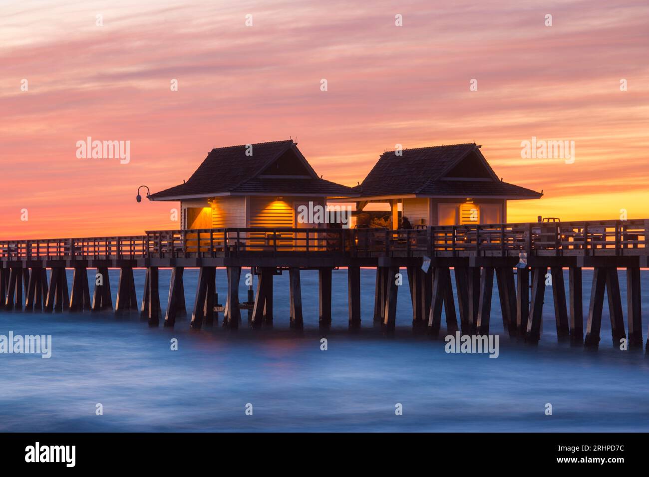 Naples, Floride, États-Unis. Cabanes en bois illuminées sur la jetée de Naples, crépuscule, ciel rose spectaculaire au-dessus du golfe du Mexique. Banque D'Images