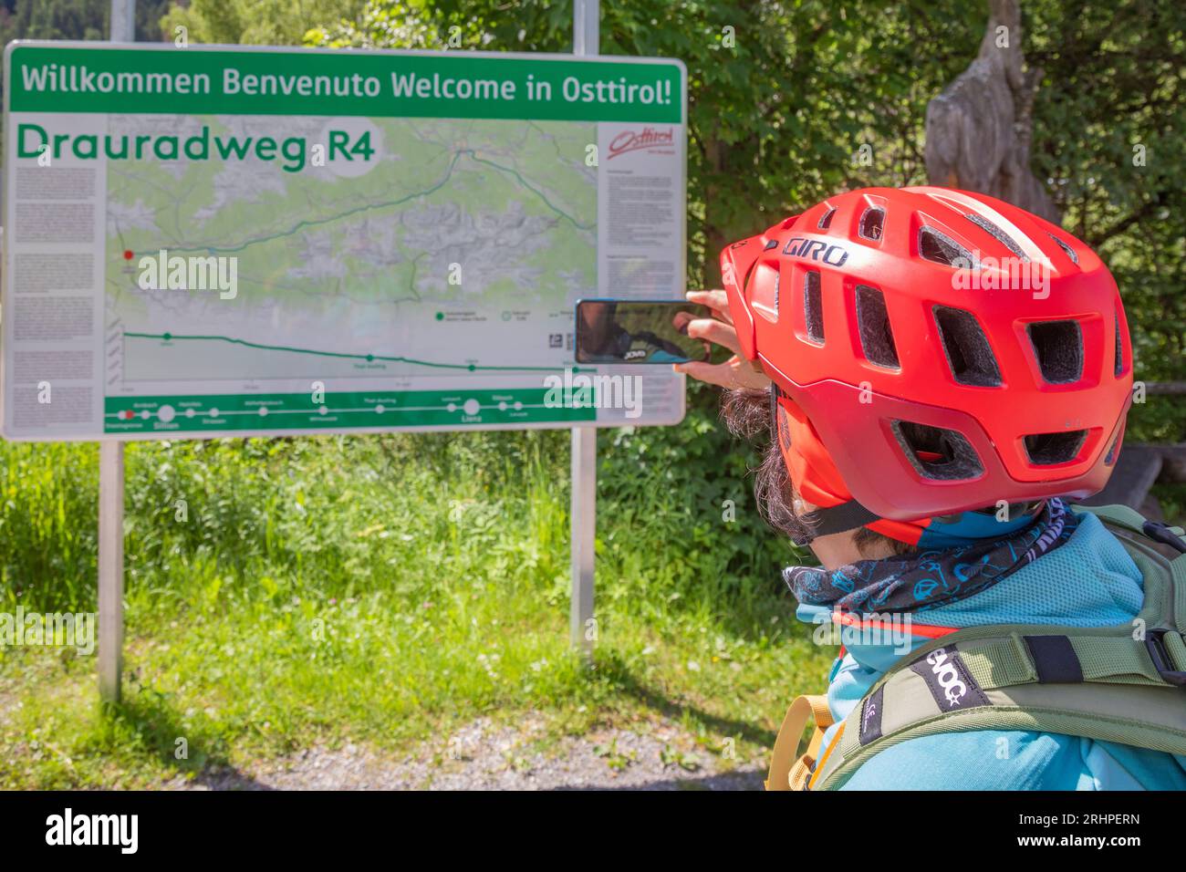 Autriche, Tyrol oriental, cycliste féminine devant le panneau d'information le long de la piste cyclable Drau entre San Candido (Innichen) et Lienz Banque D'Images