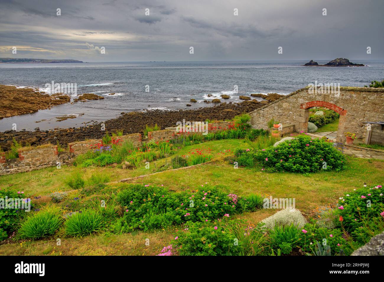 Un jardin clos avec une vue imprenable sur le récif de Brisons sous un ciel sombre et spectaculaire à Cape Cornwall, nr LANd's End, Cornwall, Angleterre, Royaume-Uni Banque D'Images