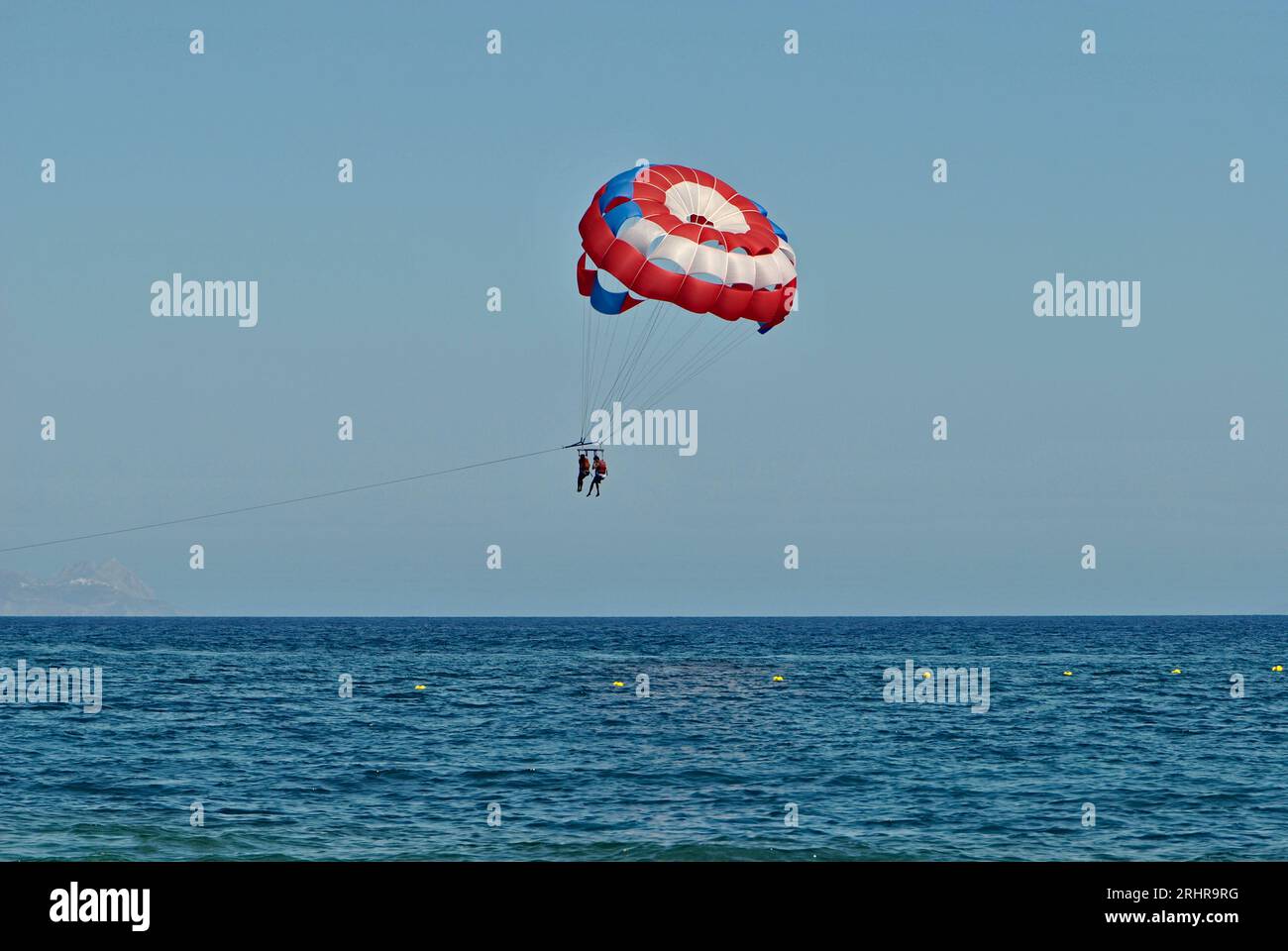 Pair profite du parachute ascensionnel pendant ses vacances d'été sur l'île de Santorin. Espace négatif. Banque D'Images
