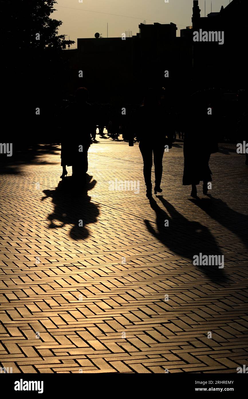 La vie quotidienne au Japon 'silhouettes de gens marchant à travers la ville illuminée par le soleil couchant' Banque D'Images