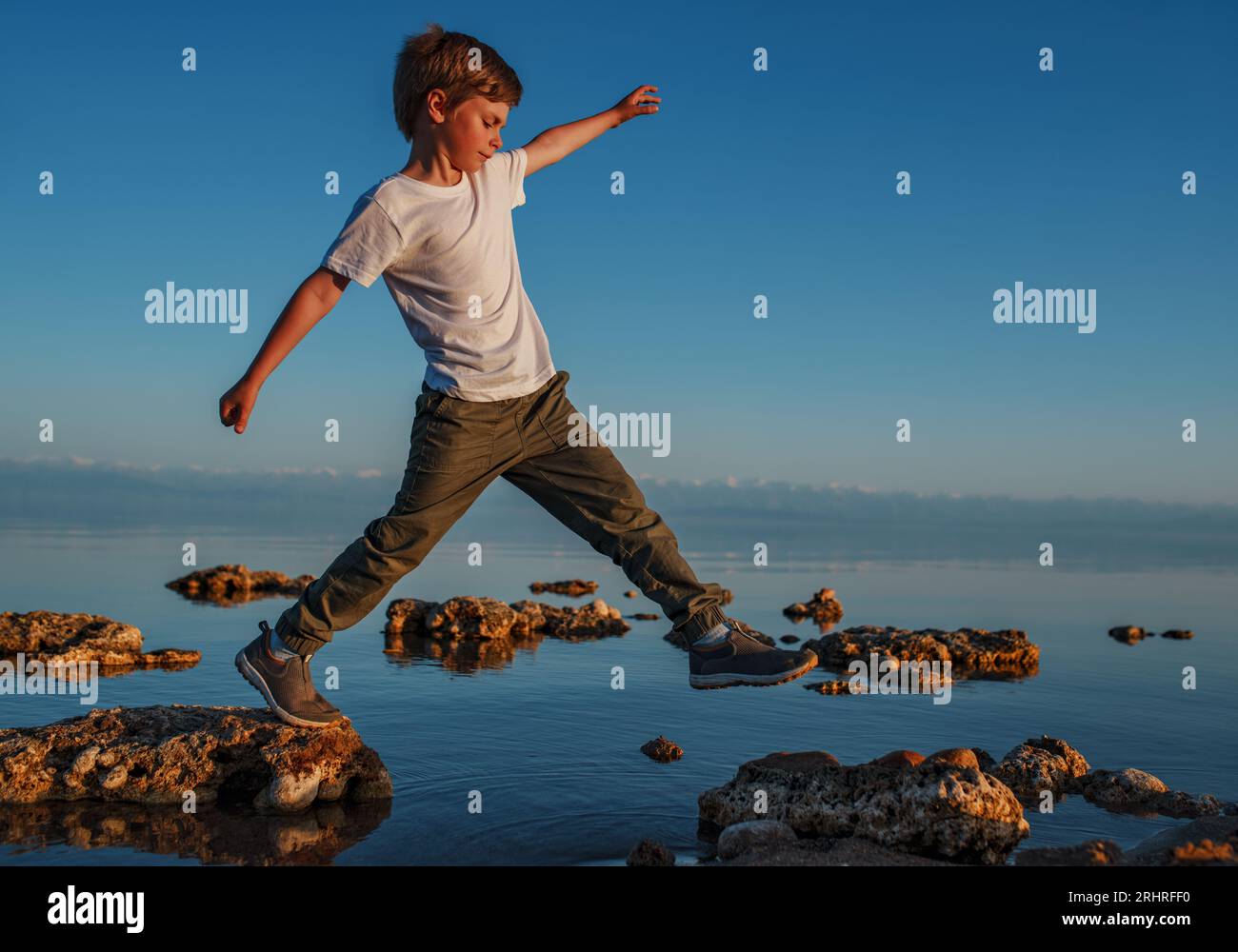 Garçon marchant sur des pierres dans le lac Banque D'Images