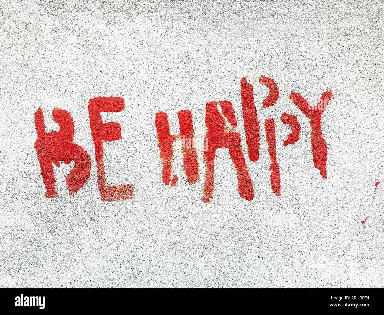 Soyez heureux écrit dans le style graffiti avec texture rugueuse isolée sur fond gris. Banque D'Images