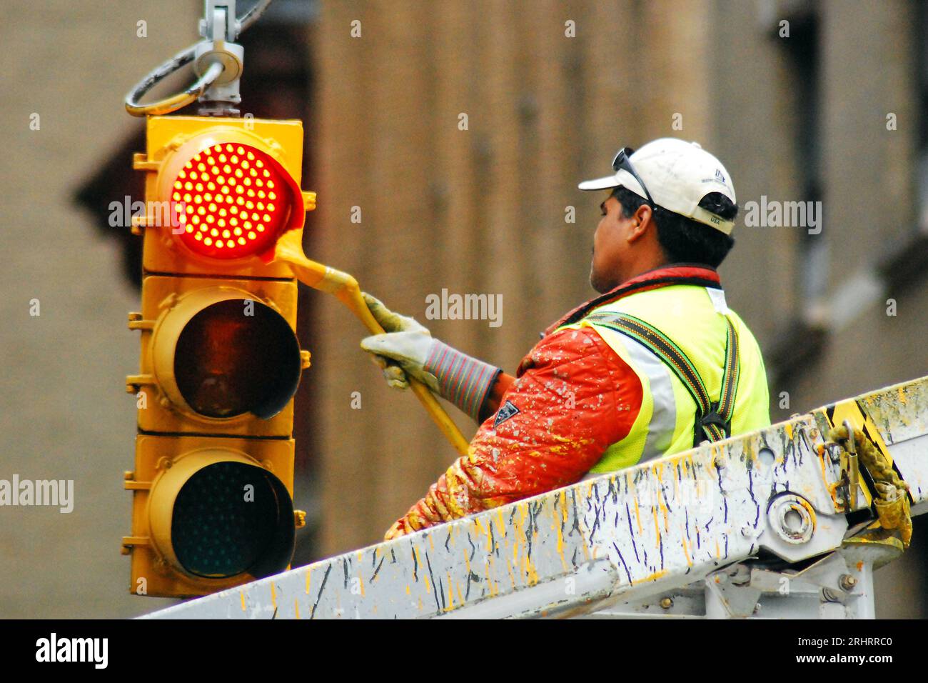 Un travailleur de la ville donne à un feu de rue de New York City une couche fraîche de peinture jaune Banque D'Images