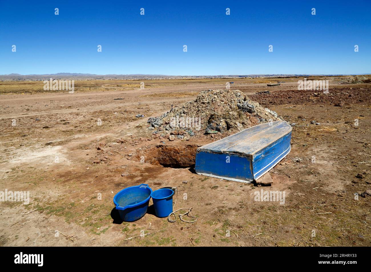 Lac Titicaca, BOLIVIE ; 18 août 2023 : un bateau à rames en bois renversé fournit de l'ombre pour un puits creusé par des villageois sur la rive asséchée de la baie de Cohana sur le lac intérieur / Huiñay Marka (la plus petite partie du lac Titicaca) près du village de Cohana. Les niveaux d'eau dans le lac Titicaca approchent du niveau record établi en 1996, le plus bas depuis que le service météorologique bolivien (Senhami) a commencé à tenir des registres en 1974. Beaucoup blâment le changement climatique ; les dernières années ont été plus sèches que la normale et El Niño se renforce actuellement dans l’océan Pacifique au large de l’Amérique du Sud. Banque D'Images