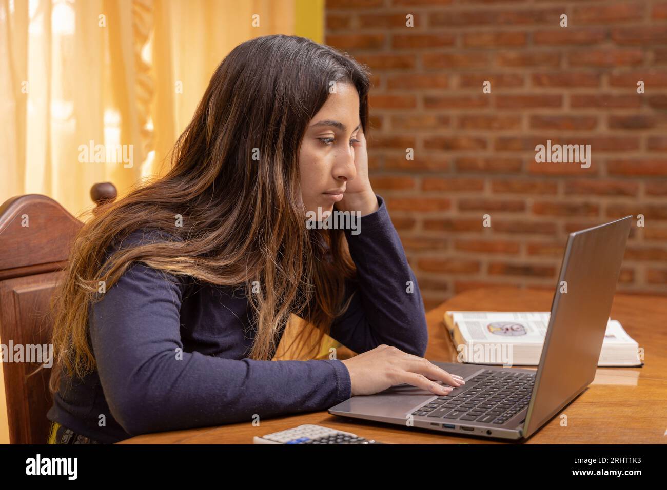 Fille latine fatiguée, étudiant devant un ordinateur portable. Banque D'Images