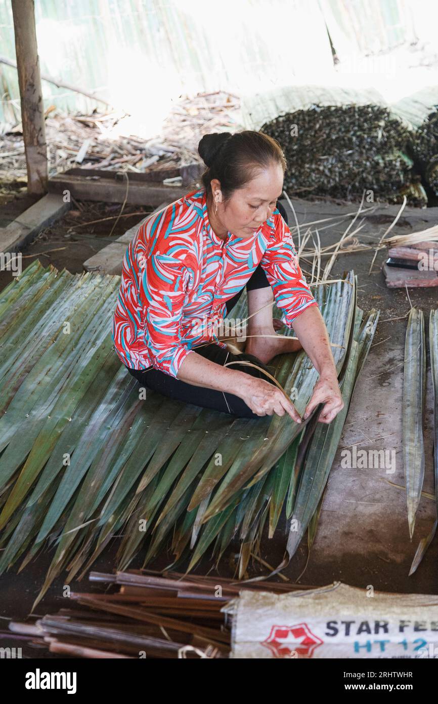 Femme cousant des feuilles de palmier ensemble au Vietnam Banque D'Images