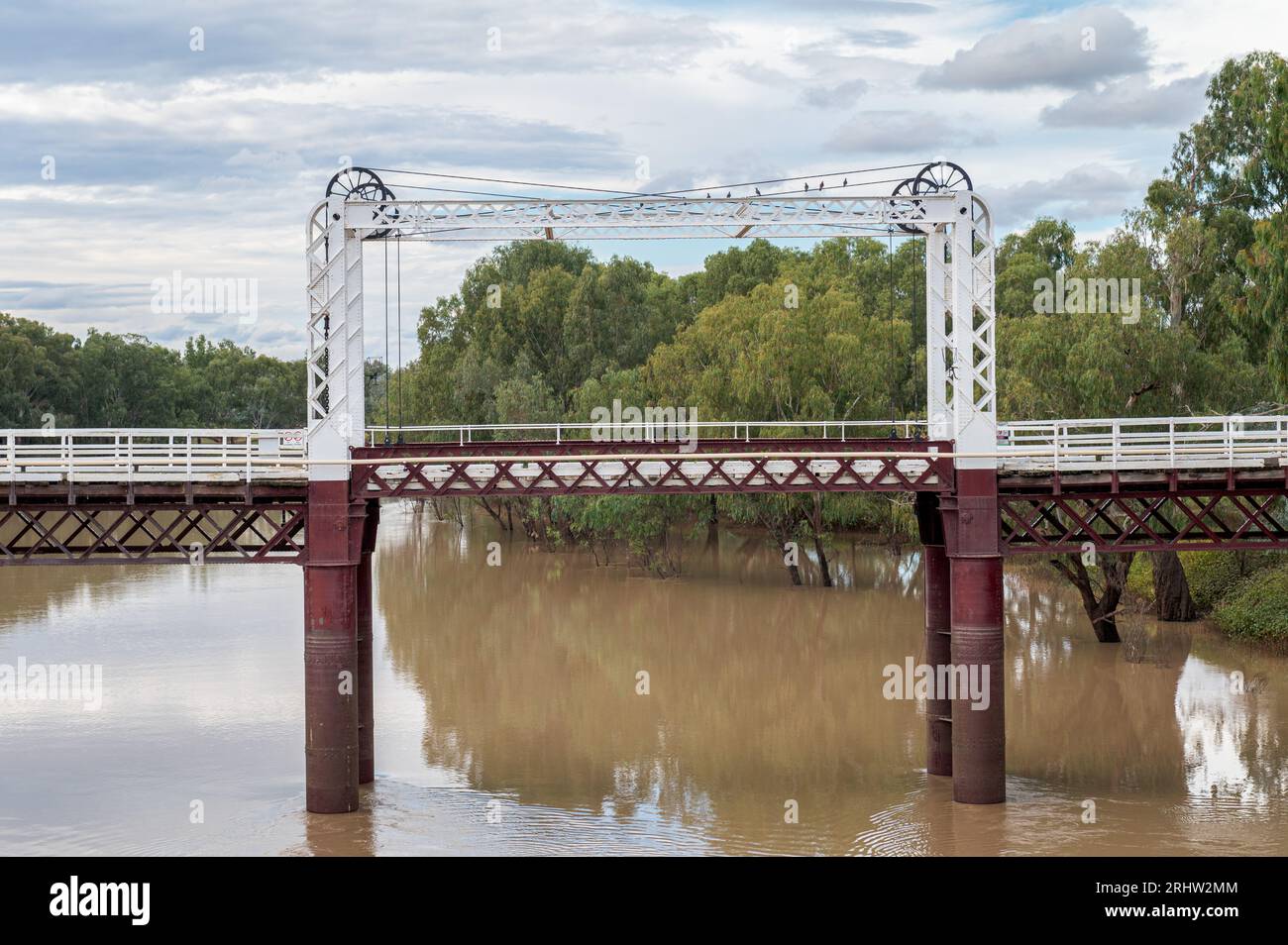 Une vue latérale sur la rivière Darling bordée de gommes rouges qui passe sous le pont historique North Bourke Draw Bridge, le plus ancien d'Australie. Banque D'Images