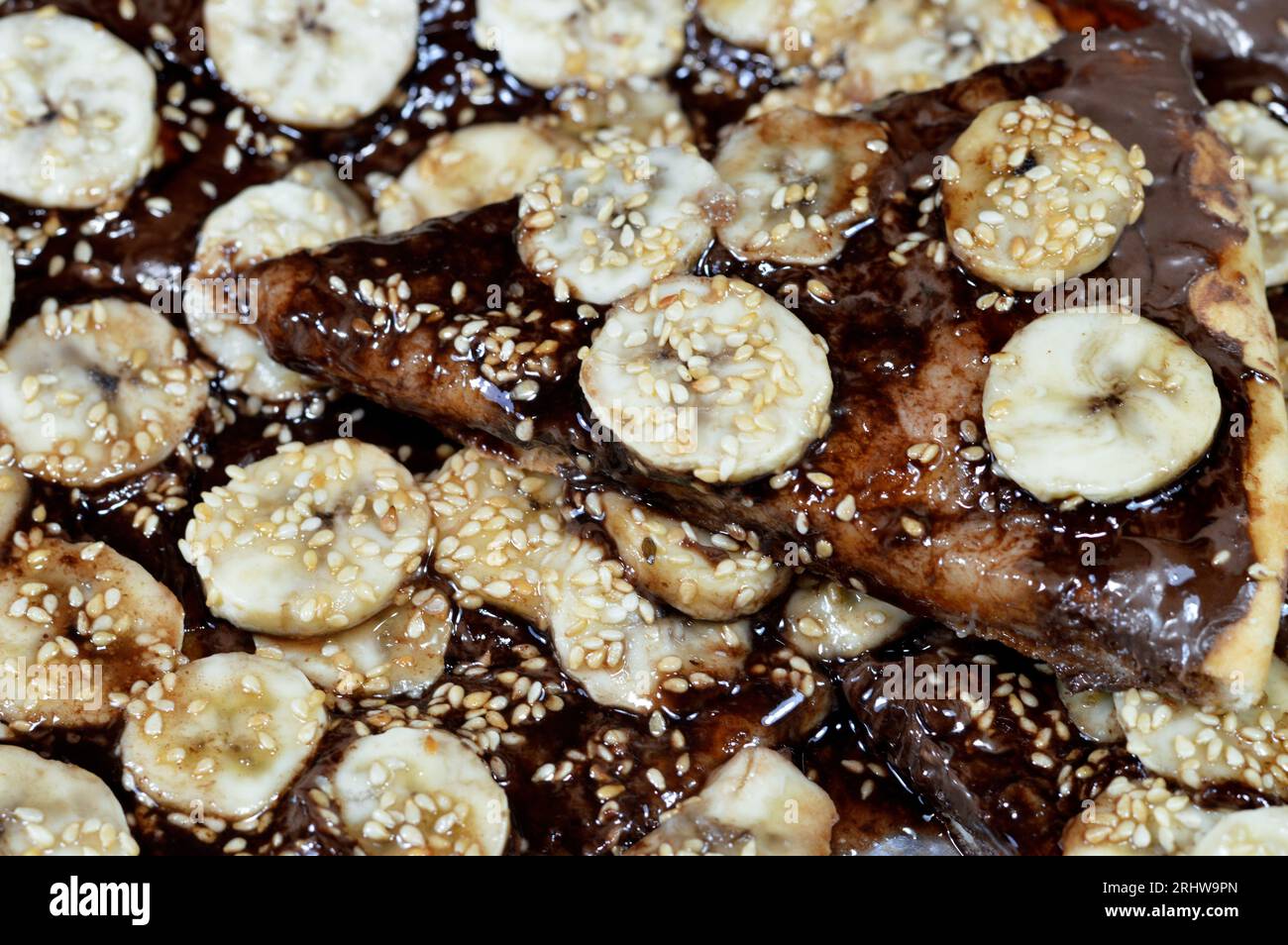 Une pâtisserie sucrée de pizza au chocolat qui cuit au four puis recouvert de chocolat fondant et garni de tranches de fruits de banane frais et se Banque D'Images