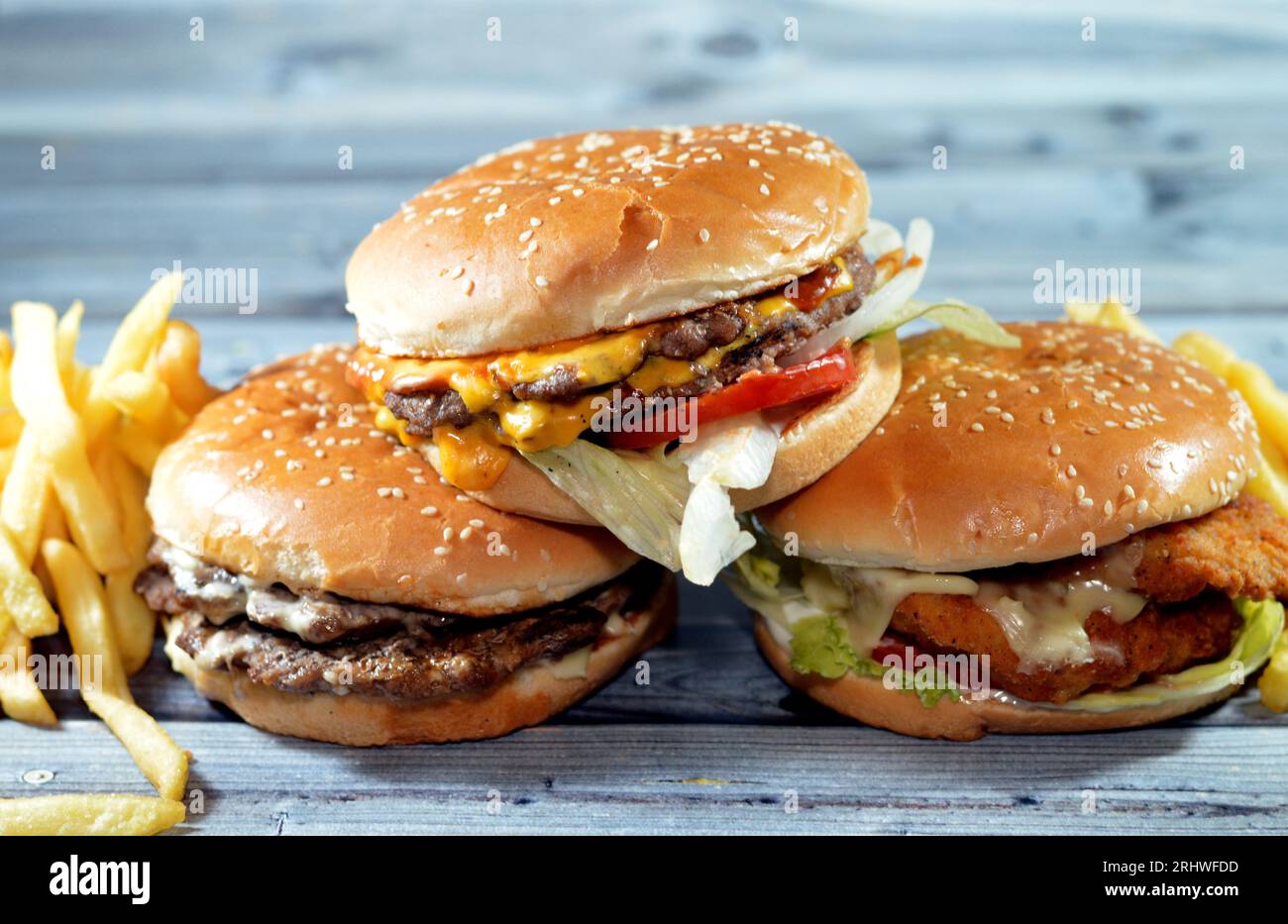 Petits pains au sésame de patties de filet de poulet pané frit, laitue croustillante, fromage fondant, oignons et sauce, pâté de bœuf double épaisse juteuse avec couverture de fromage Banque D'Images