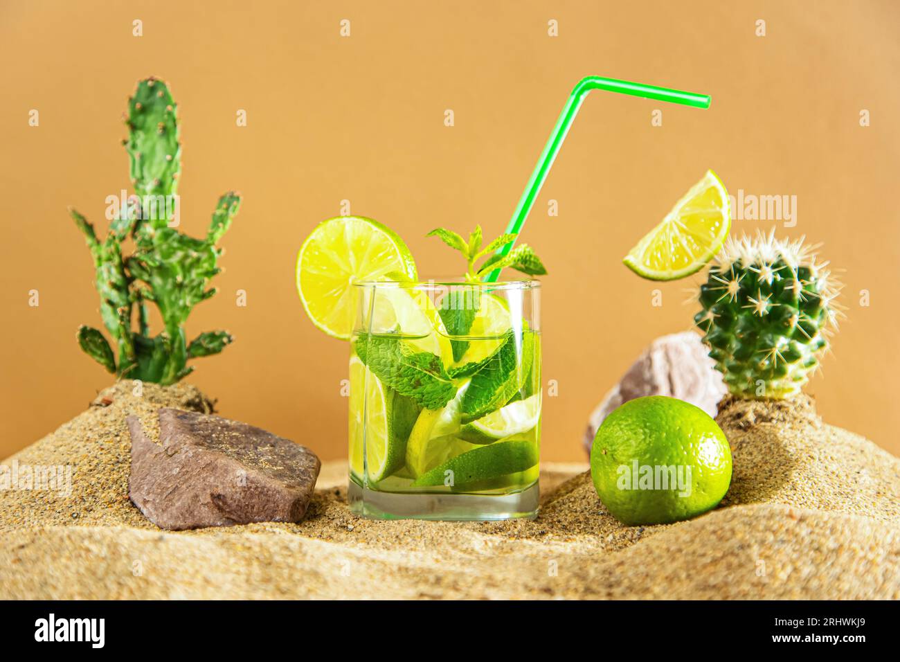 Verre de limonade à la chaux et à la menthe parmi les dunes de sable et les cactus. Fond beige. Banque D'Images