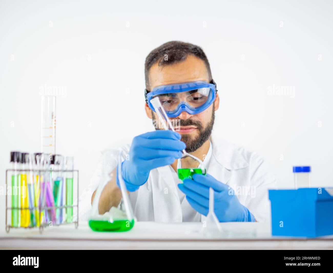Jeune homme scientifique observant une fiole jaugée avec un liquide vert à l'intérieur. Banque D'Images