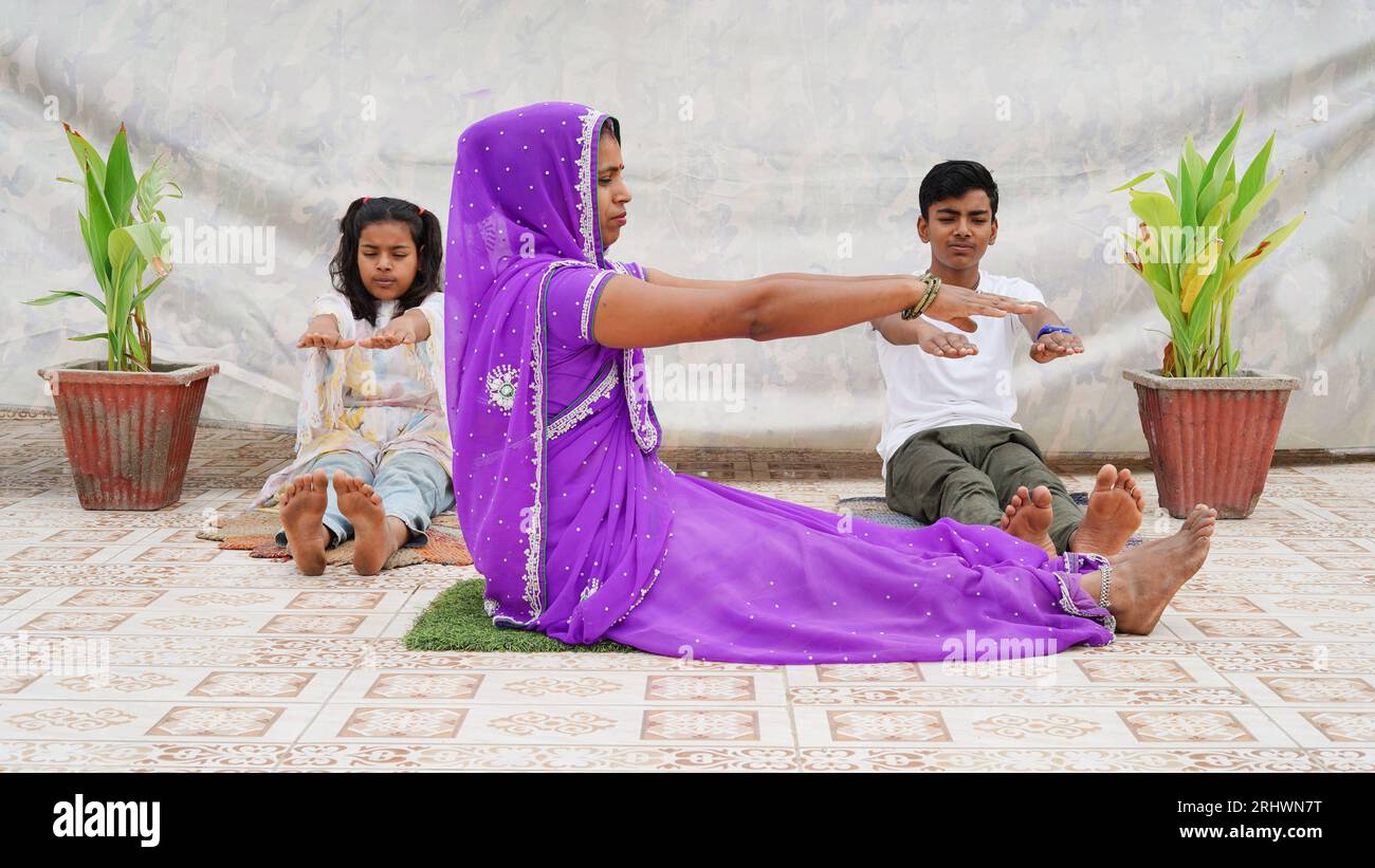 Mère indienne pratiquant des exercices de yoga avec des enfants à l'extérieur dans la pose méditée ensemble Banque D'Images