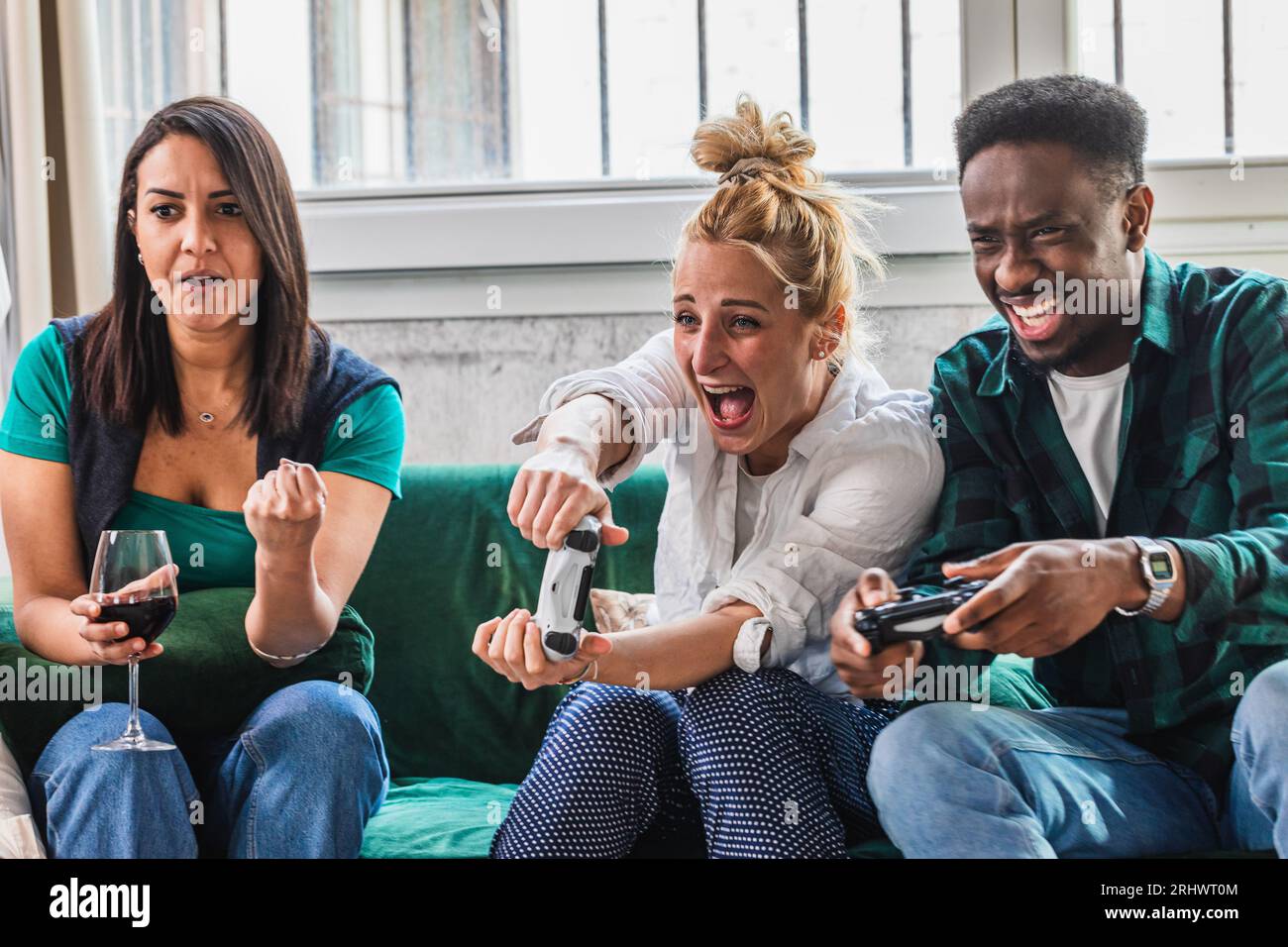 Jeunes amis enthousiastes jouant à des jeux vidéo. Jeu chauffé et gestes d'exultation. Soirée à la maison jouant à l'ordinateur et console de jeux. Contrôleur en h Banque D'Images