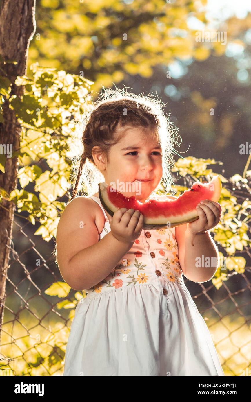 Mignonne petite fille mangeant de la pastèque à l'extérieur Banque D'Images