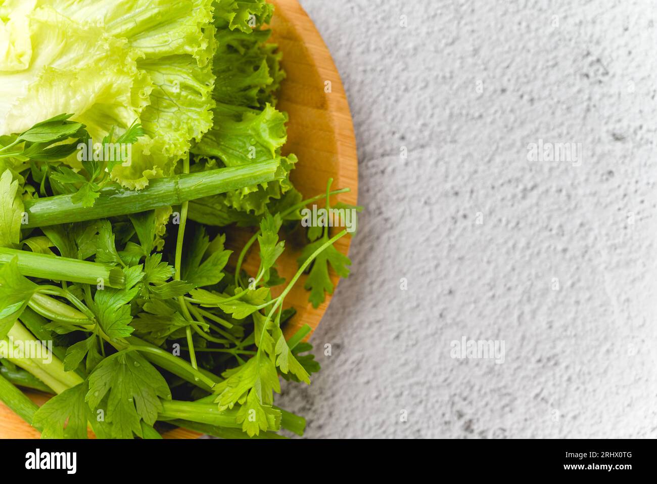 Oignons verts biologiques, ciboulette, laitue et persil sur la table en pierre Banque D'Images