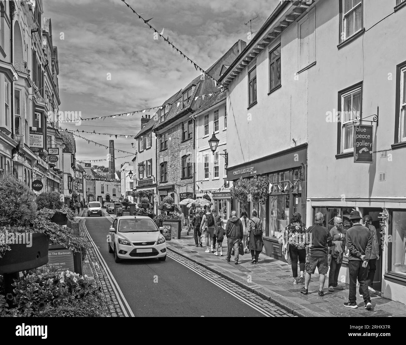 L'image monochrome de Flower Tubs et de Bunting apporte une sensation festive à Southside Street sur la Barbican historique de Plymouth. Un mélange original de petites boutiques, Banque D'Images
