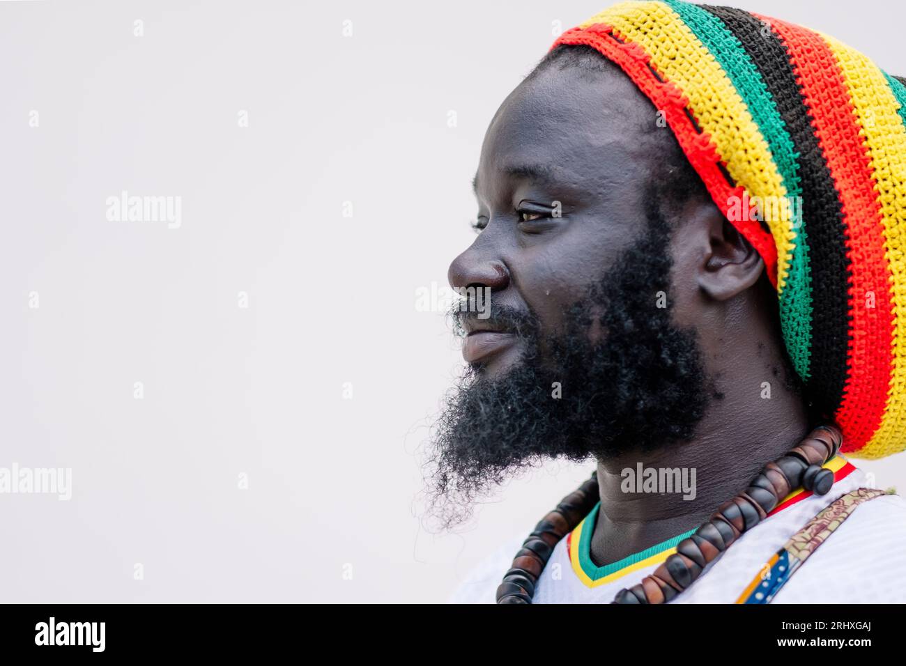 Vue latérale de l'homme afro-américain dans le chapeau coloré debout et regardant loin sur fond blanc Banque D'Images