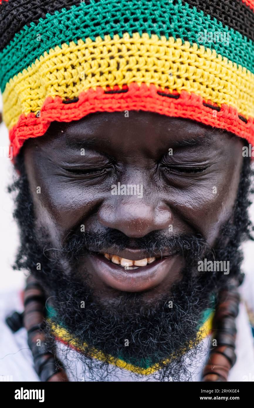 Gros plan de l'homme afro-américain dans le chapeau coloré debout avec les yeux fermés sur fond blanc Banque D'Images