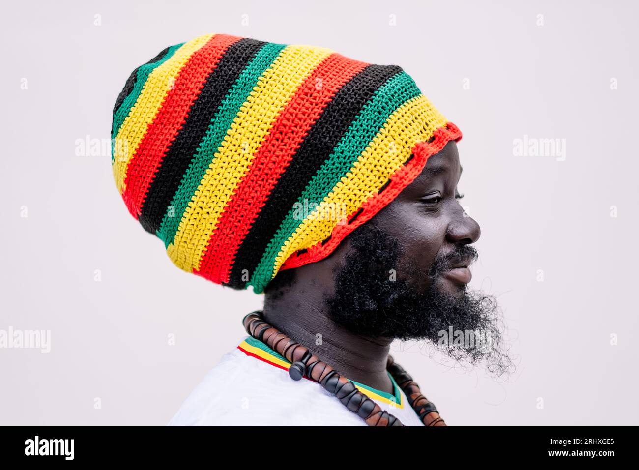 Vue latérale de l'homme afro-américain dans le chapeau coloré debout et regardant loin sur fond blanc Banque D'Images