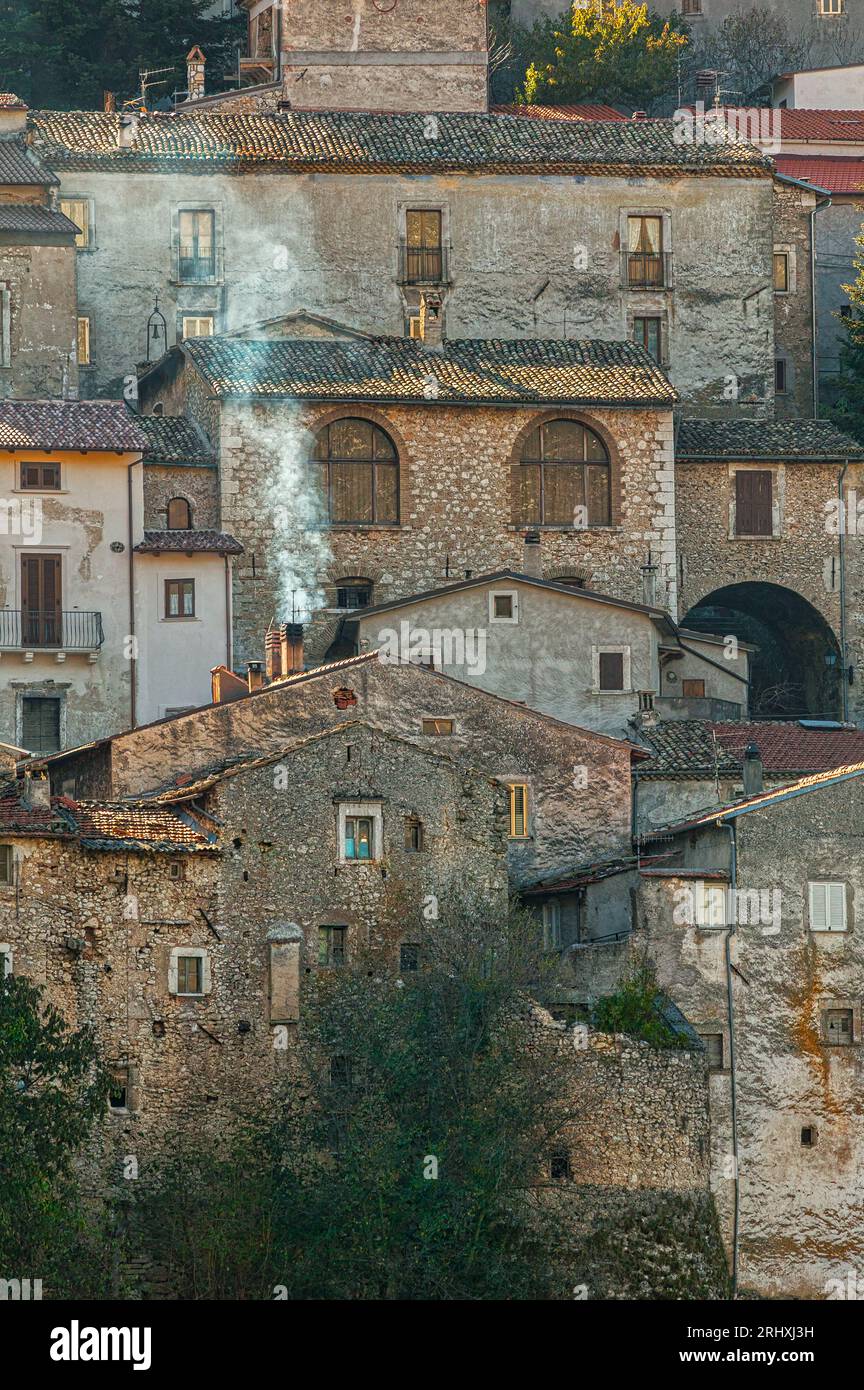 Le petit village touristique d'Ortona dei Marsi rétroéclairé par la première lumière d'hiver avec la fumée sortant des cheminées des maisons.Abruzzes Banque D'Images