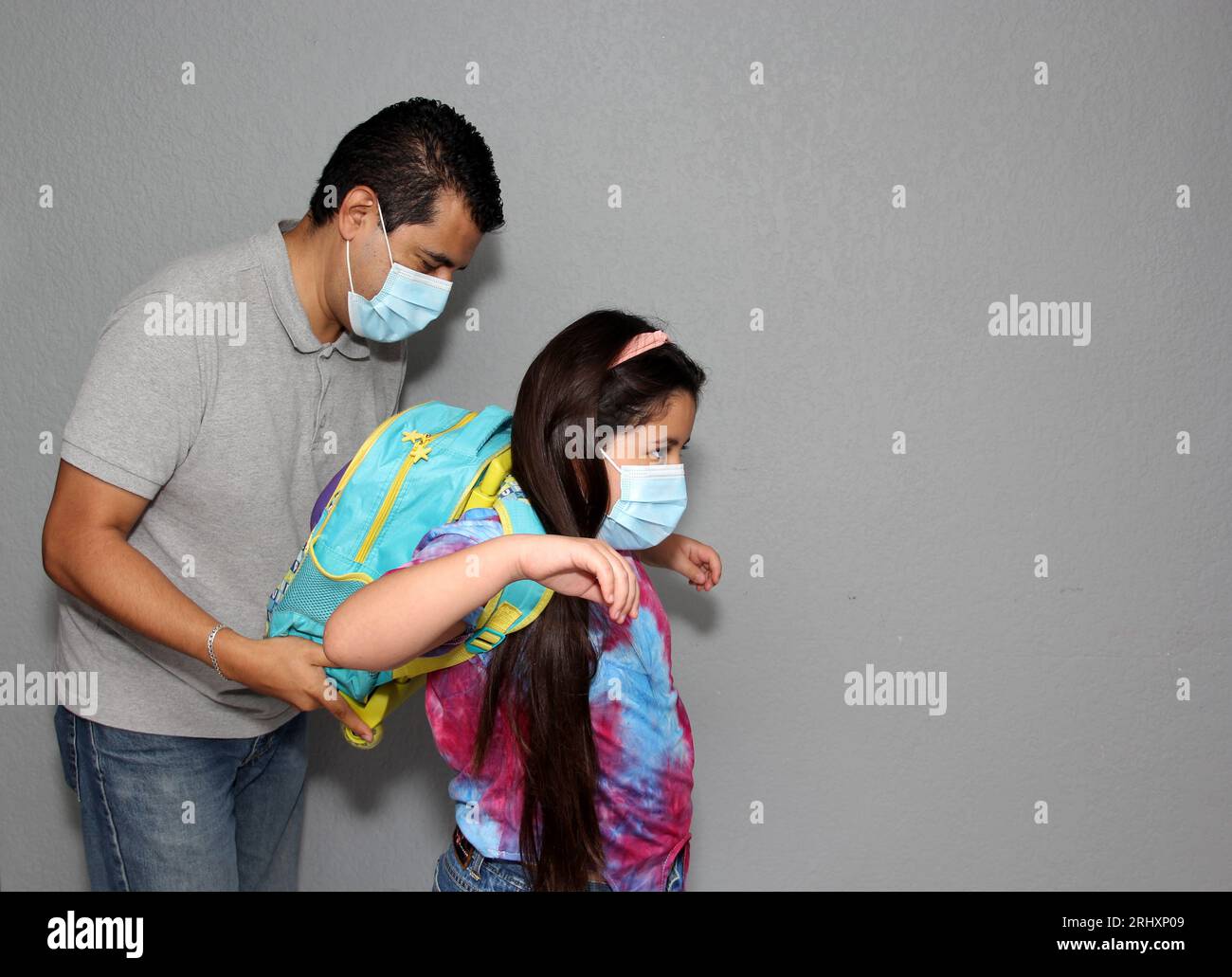 Père et fille latinos avec des masques faciaux et un sac à dos prêts à retourner à l’école dans la nouvelle normalité en raison de la pandémie de Covid-19 Banque D'Images