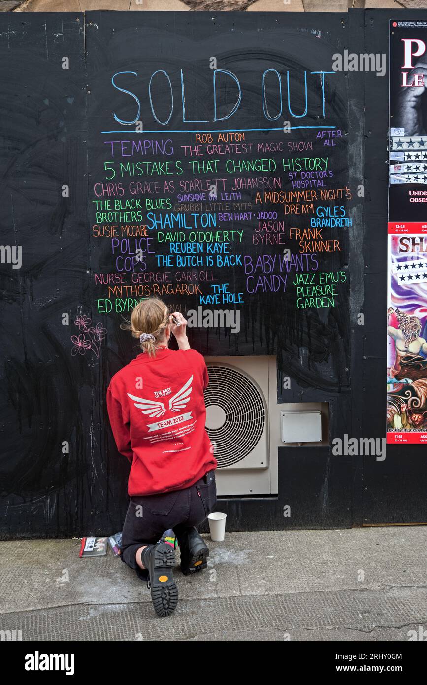 Jeune femme de l'Assemblée mettant à jour le tableau noir des spectacles à guichets fermés. Edimbourg Fringe 2023. Banque D'Images