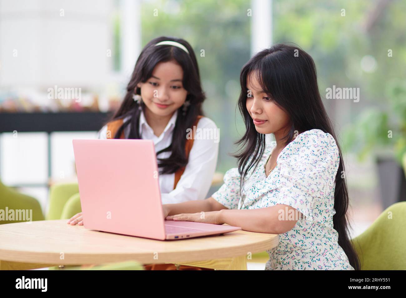 Belle adolescente avec ordinateur portable. Jeunes amies travaillant sur ordinateur dans le restaurant. Étudiant faisant ses devoirs. Travail en ligne freelance. Banque D'Images