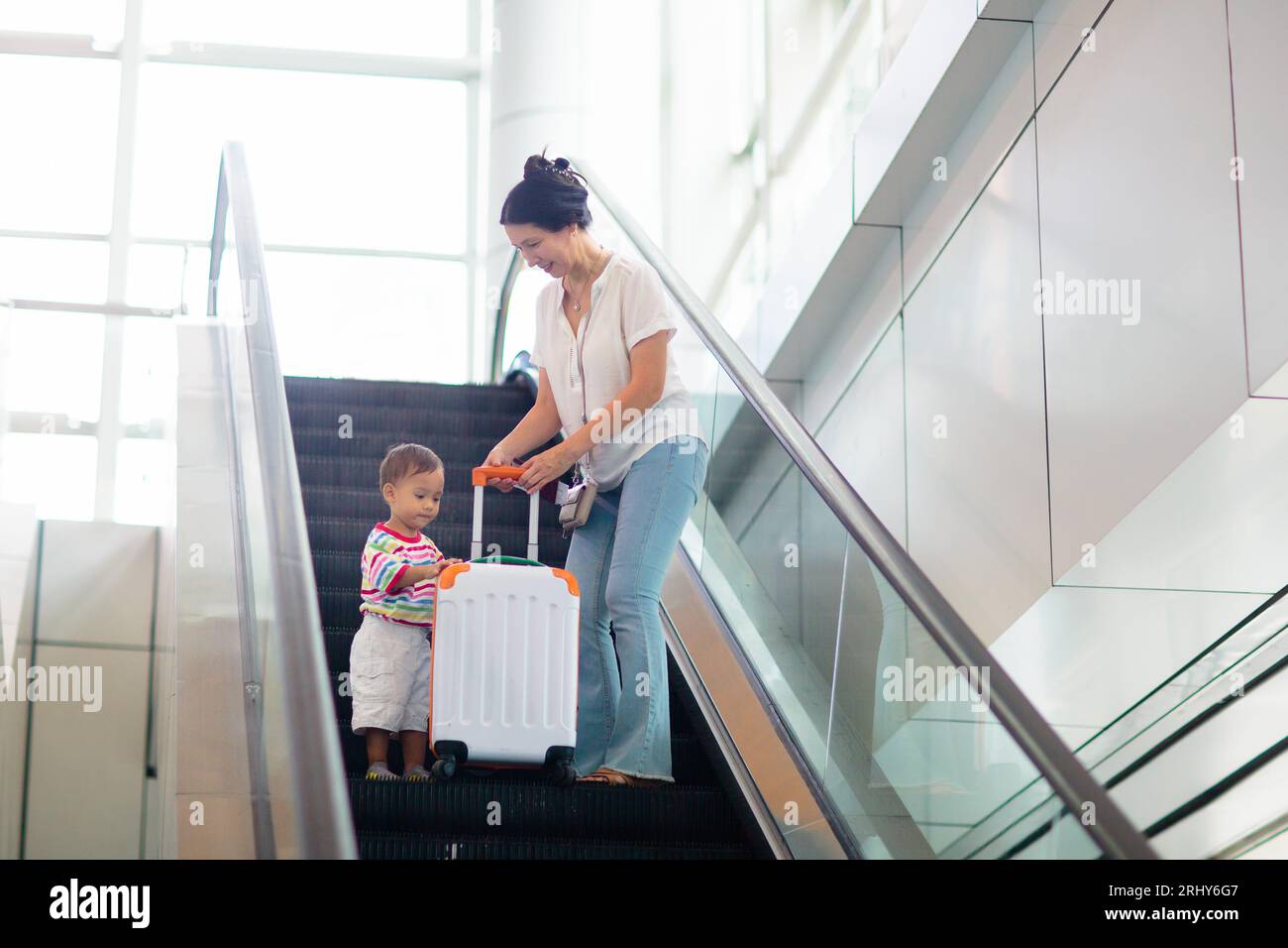 Famille à l'aéroport. Jeune mère asiatique et enfant voyagent par avion. Volez avec des enfants. Femme et bébé garçon marchant à l'avion à l'intérieur du hall du terminal de l'aéroport. Banque D'Images