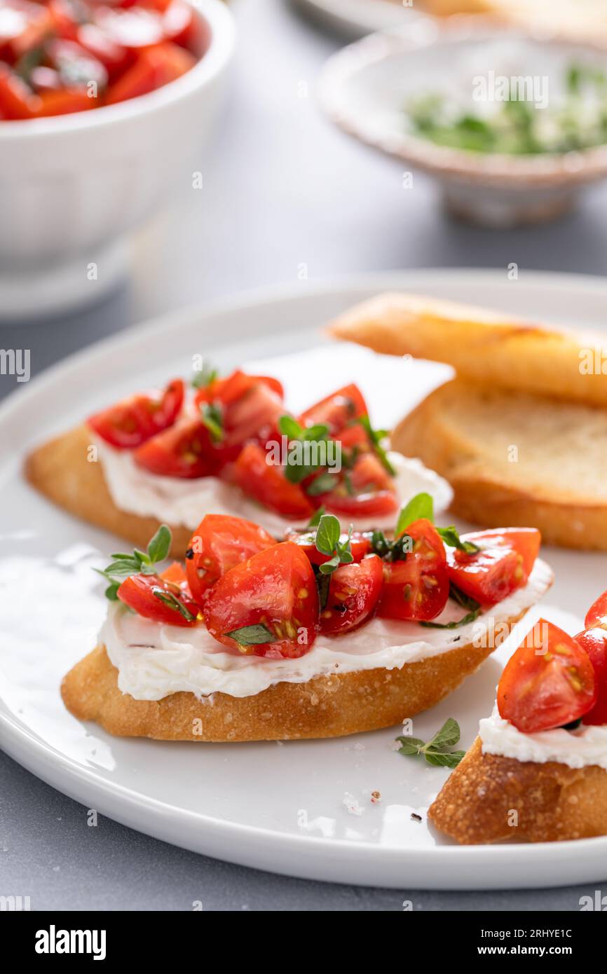 Bruschettas de tomates au basilic et au fromage à la crème avec tomates cerises fraîches et herbes Banque D'Images