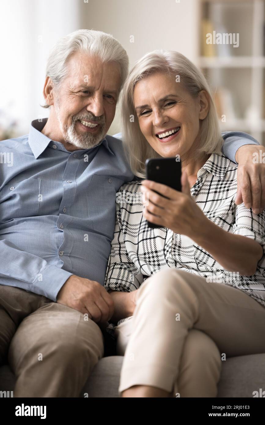 Joyeux vieux mari et femme retraités utilisant smartphone ensemble Banque D'Images