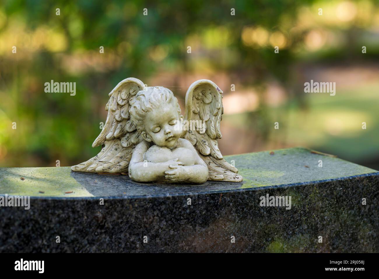 Petit ange sur la pierre tombale avec un cœur dans les bras Banque D'Images