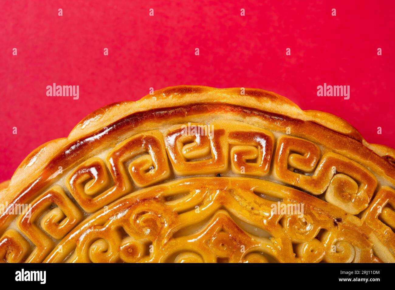 Partie d'un gâteau de lune chinois traditionnel sur rouge avec la composition horizontale de l'espace de copie Banque D'Images