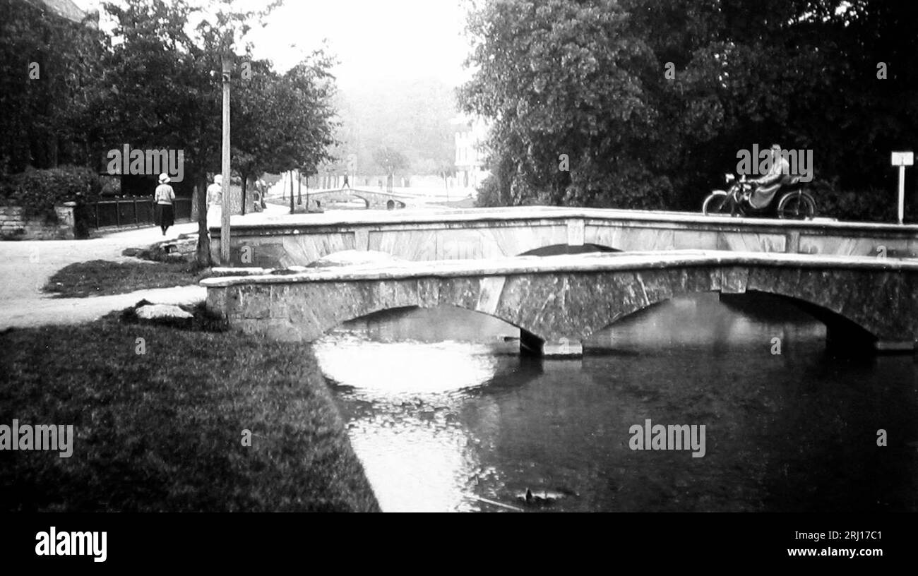 Motocycliste sur un pont à Bourton on the Water, probablement dans les années 1920 Banque D'Images