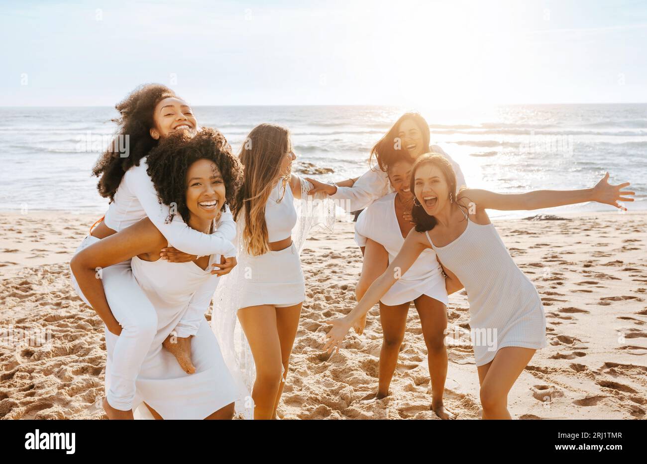 Des dames ludiques et diverses se cognent les unes les autres sur la plage, ayant une fête de poule et des dupes autour, espace de copie Banque D'Images