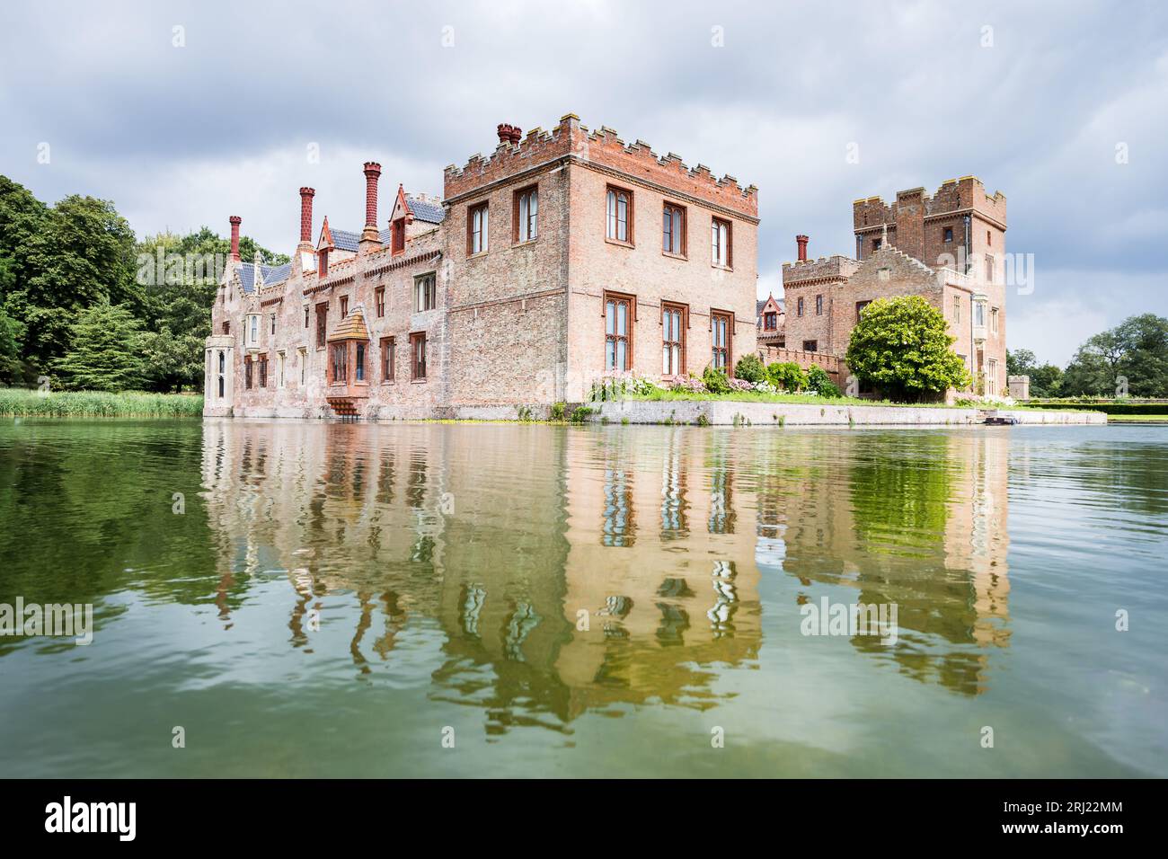 Oxburgh Hall se reflétant dans l'eau de ses douves environnantes vu lors d'une journée d'été brillante à Norfolk en août 2023. Banque D'Images