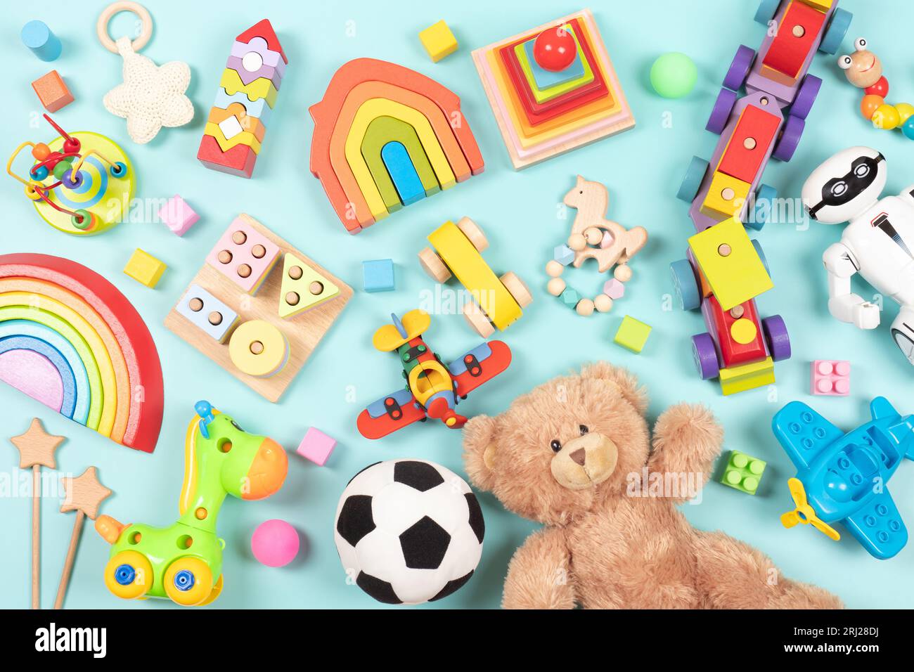 Modèle de jouets pour bébés enfants. Ensemble de jouets éducatifs colorés en bois et pelucheux pour les enfants sur fond bleu clair. Vue de dessus, pose à plat Banque D'Images