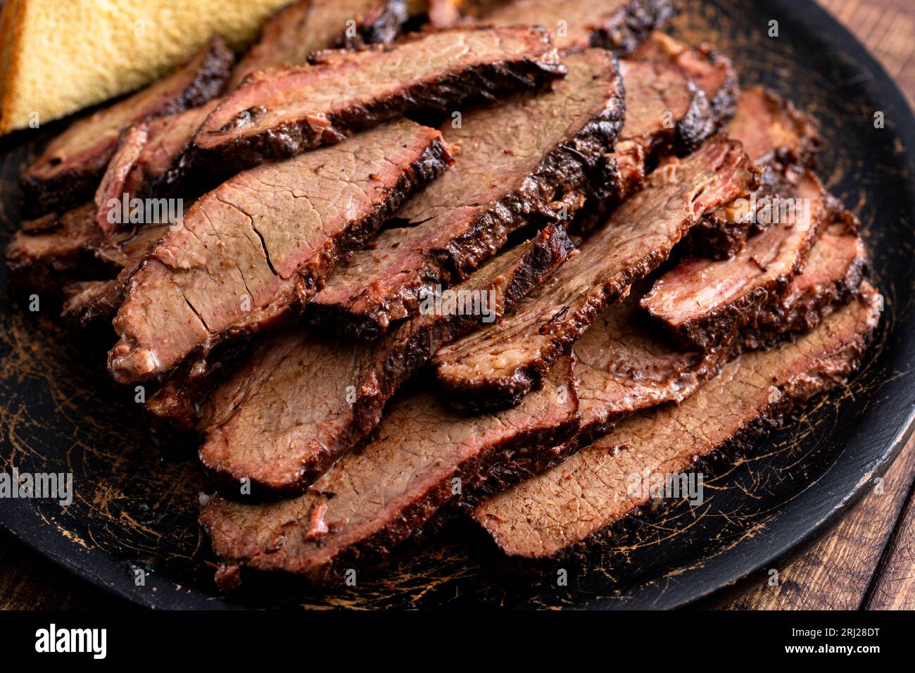 Tranche de poitrine fumée sur une assiette de service avec pain grillé servi avec sauce barbecue Banque D'Images