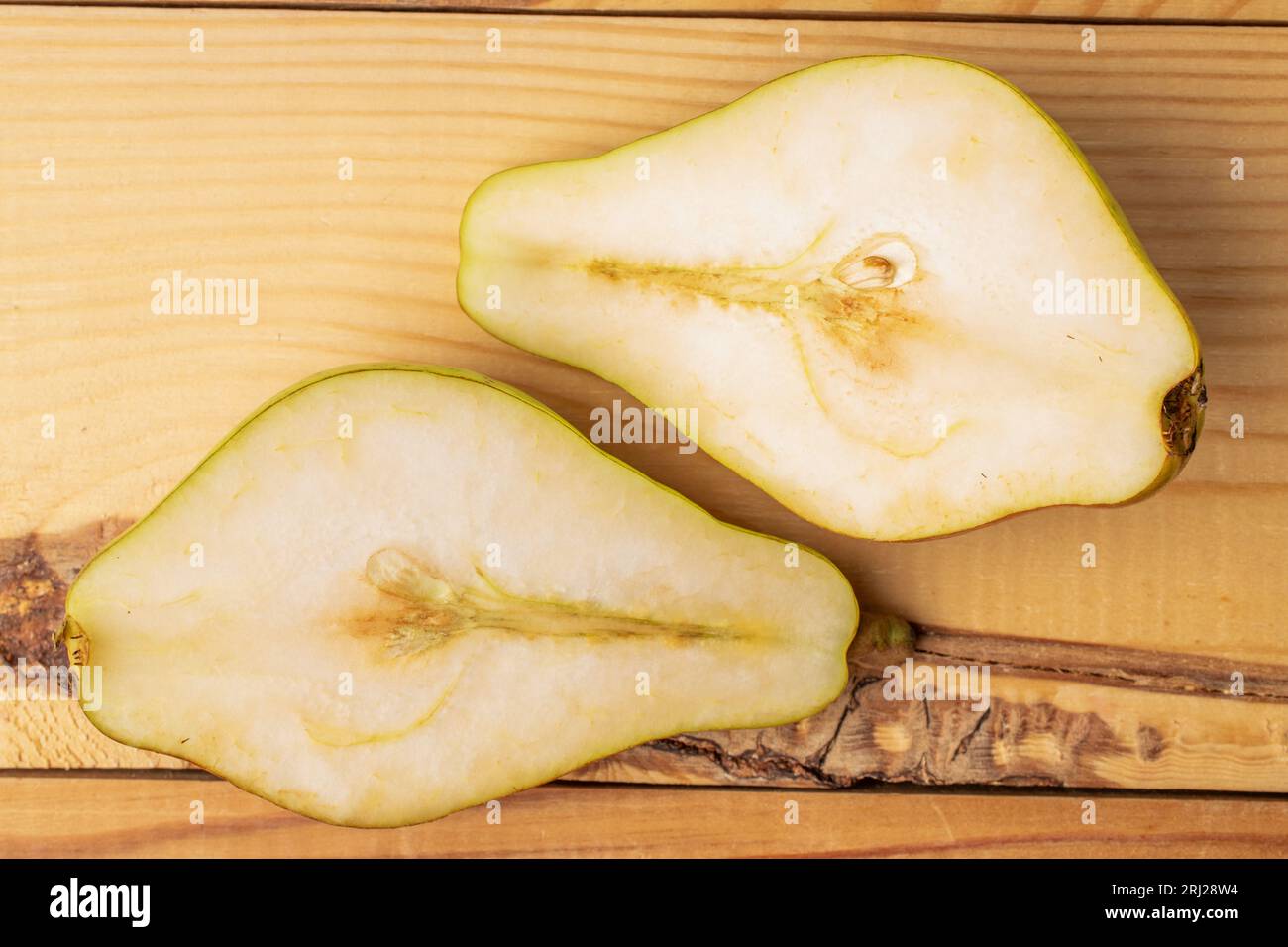 Deux moitiés d'une poire juteuse mûre, gros plan, sur une table en bois, vue de dessus. Banque D'Images