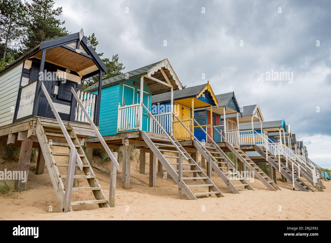 Cabanes de plage à Wells à côté de la mer sur la côte nord de Norfolk photographié au-dessus de la plage de sable doré sur pilotis en bois pour les protéger des marées hautes. Banque D'Images