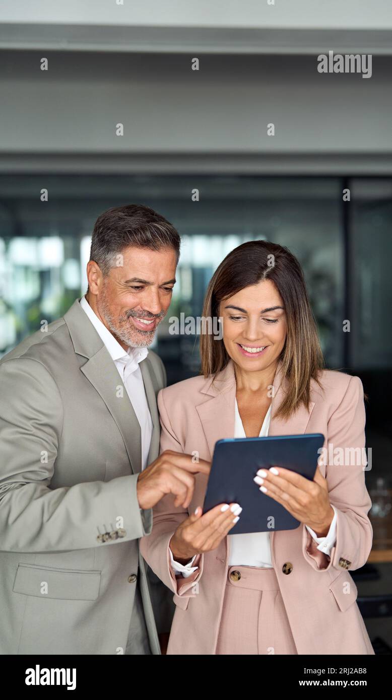 Deux cadres professionnels utilisant une tablette debout au bureau. Banque D'Images