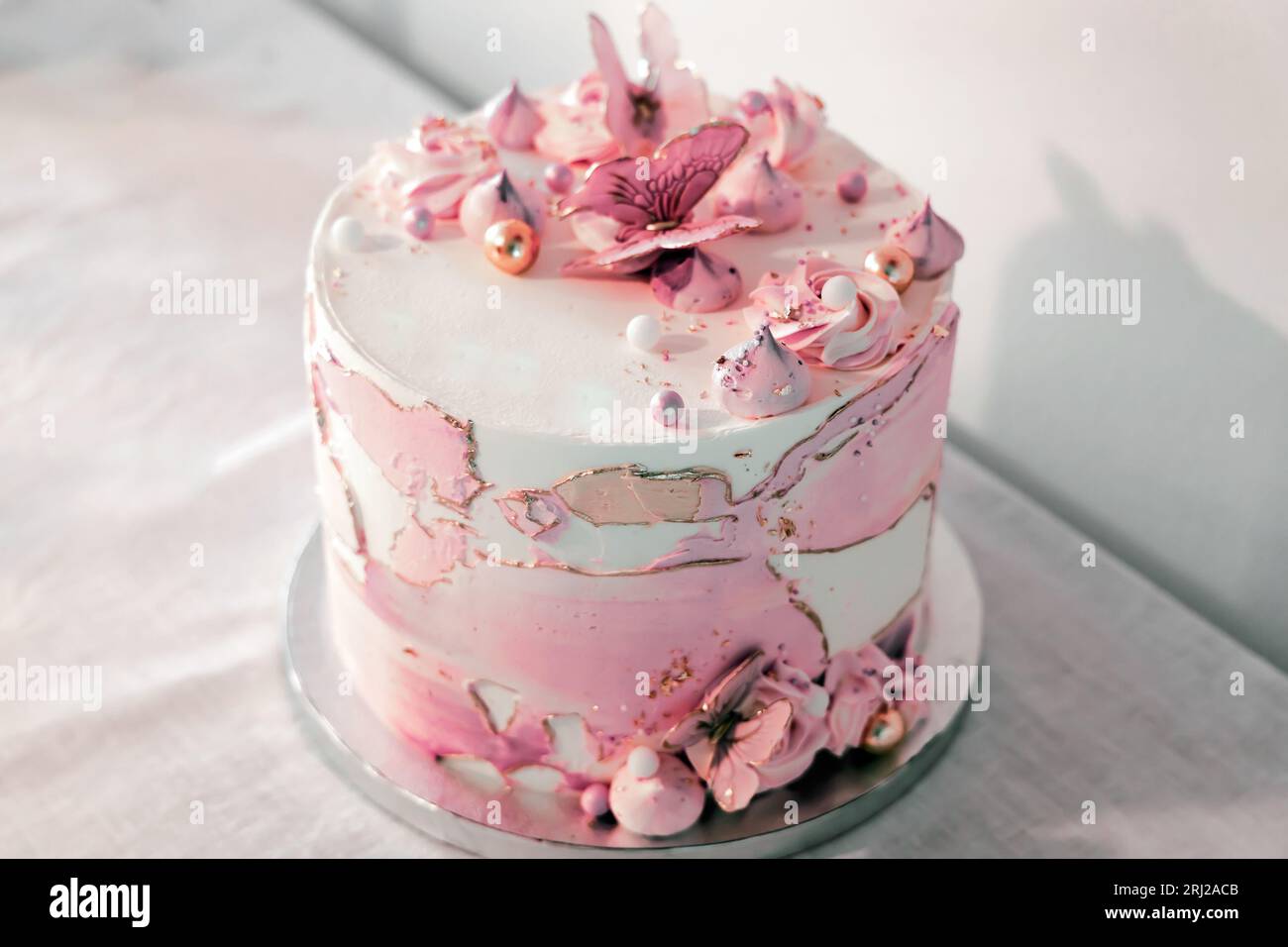 Gâteau d'anniversaire décoré avec des fleurs de sucre rose et des papillons. Banque D'Images