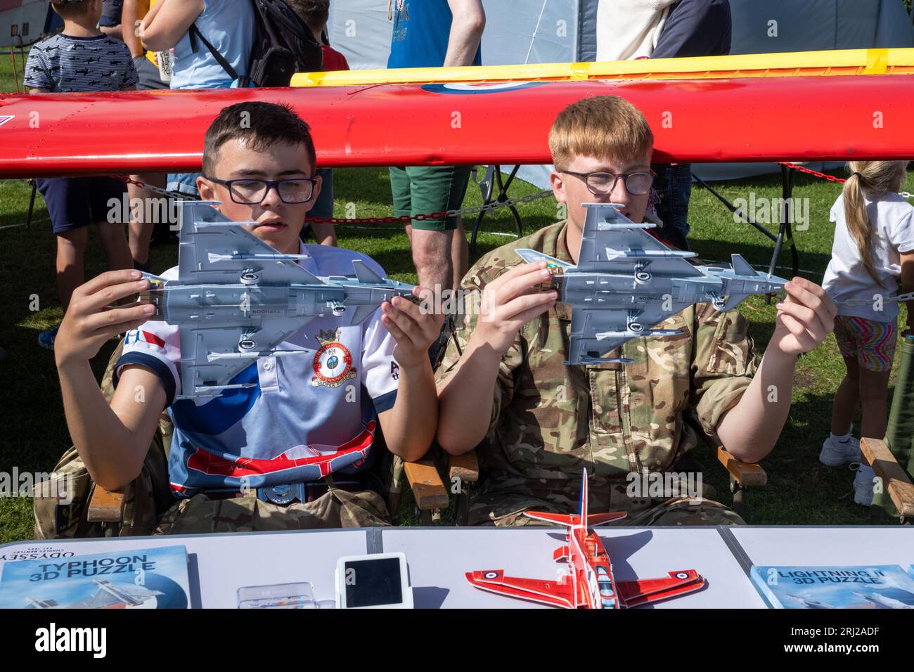 Deux jeunes cadets de l'Air en uniforme militaire tiennent des maquettes d'avions Typhoon sur un stand d'exposition dans l'exposition militaire aux côtés de l'annuel Eastbourne Airb Banque D'Images