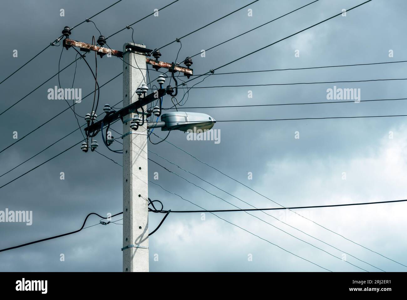 Ancien service public d'électricité et poteau de lumière de rue avec des câbles et des fils contre le ciel dramatique, mise au point sélective Banque D'Images