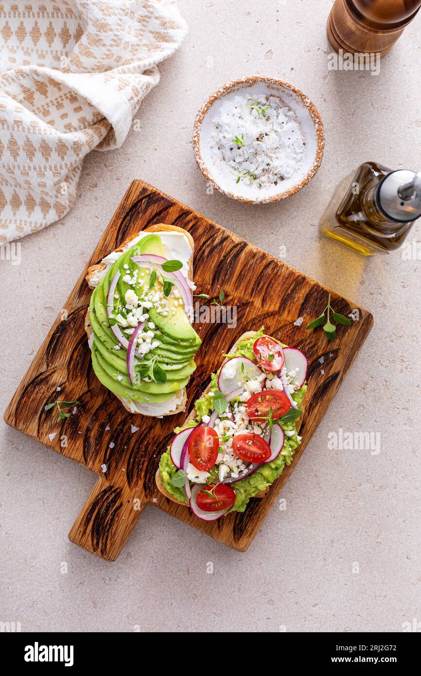 Toasts d'avocat avec radis, tomates et feta garnis d'huile d'olive, idée de petit déjeuner sain Banque D'Images